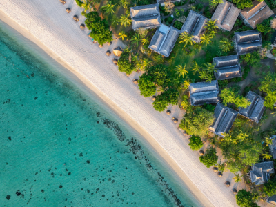 Admire the stunning aerial beauty of Mauritius, showcasing luxury beachfront villas, lush tropical gardens, and crystal-clear lagoons stretching along the coastline.