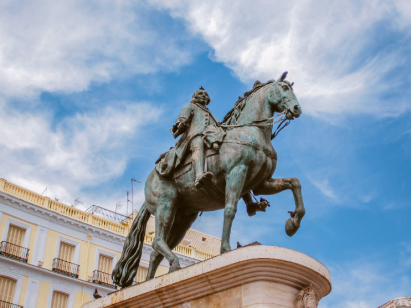 Equestrian statue in Madrid's historic city center surrounded by classic Spanish architecture